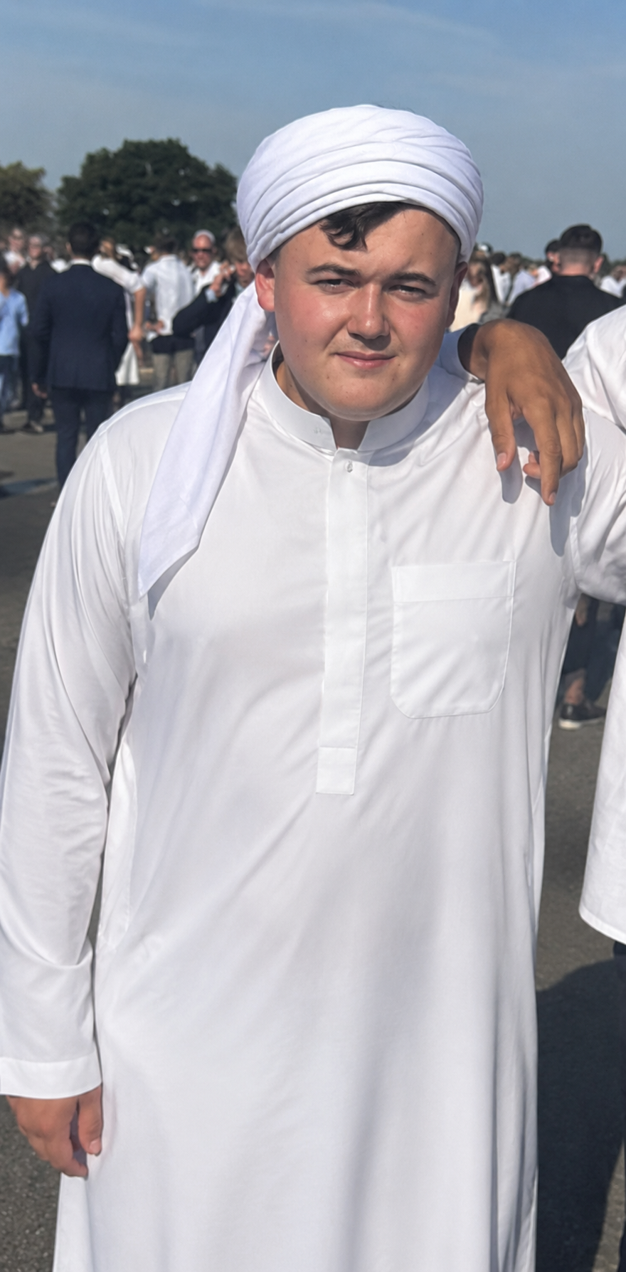 Young community member wearing white traditional clothing at a mosque gathering